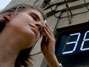 Jovem russa enxuga o suor da cara enfrente a term�metro que marca 38�C. Foto: AFP