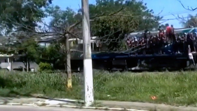 Passageiros viajam segurando em portas e janelas em trem da Baixada Fluminense